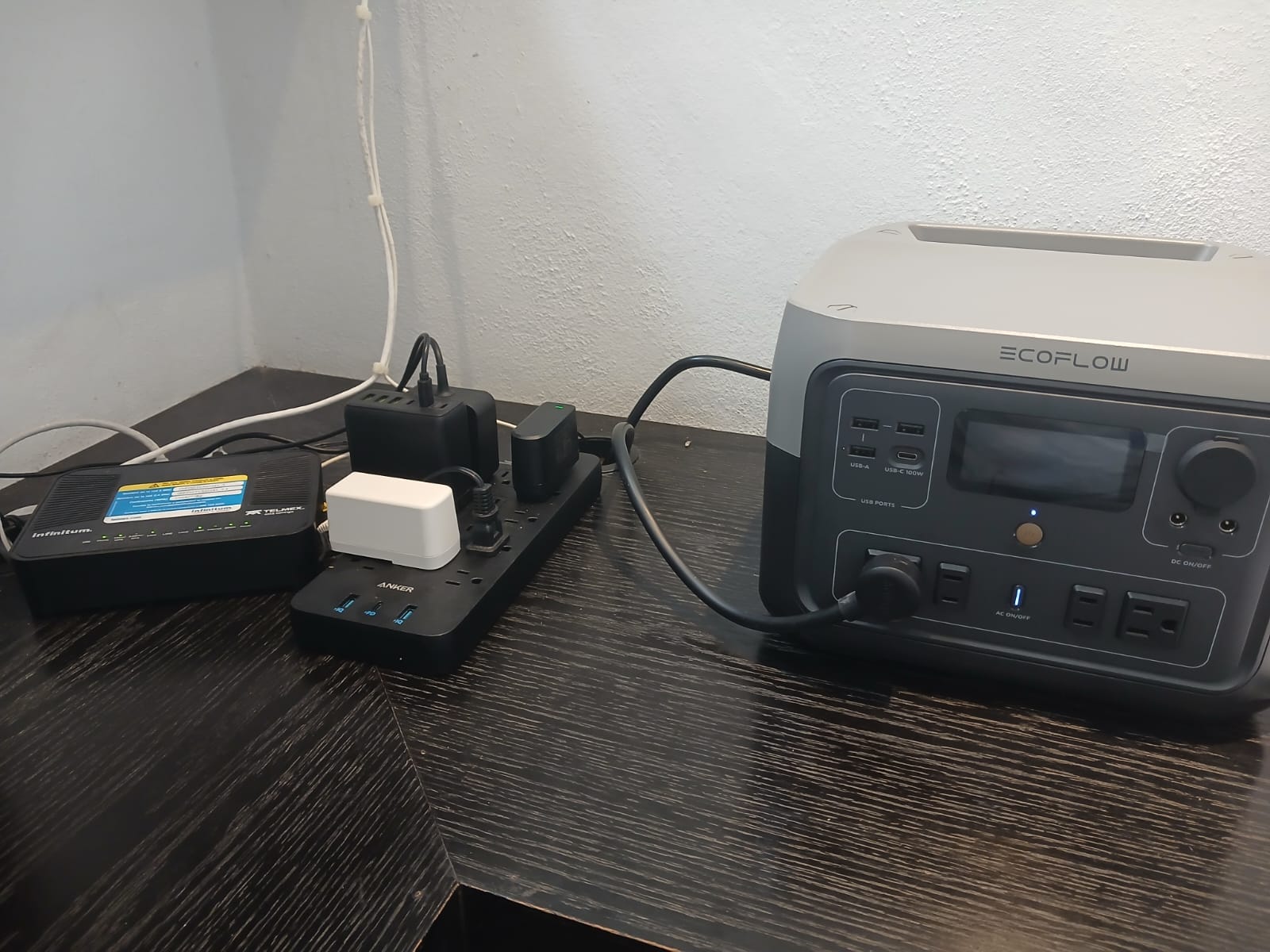 An EcoFlow portable power station connected to a Telmex modem and an Anker surge-protected power strip on a desk
